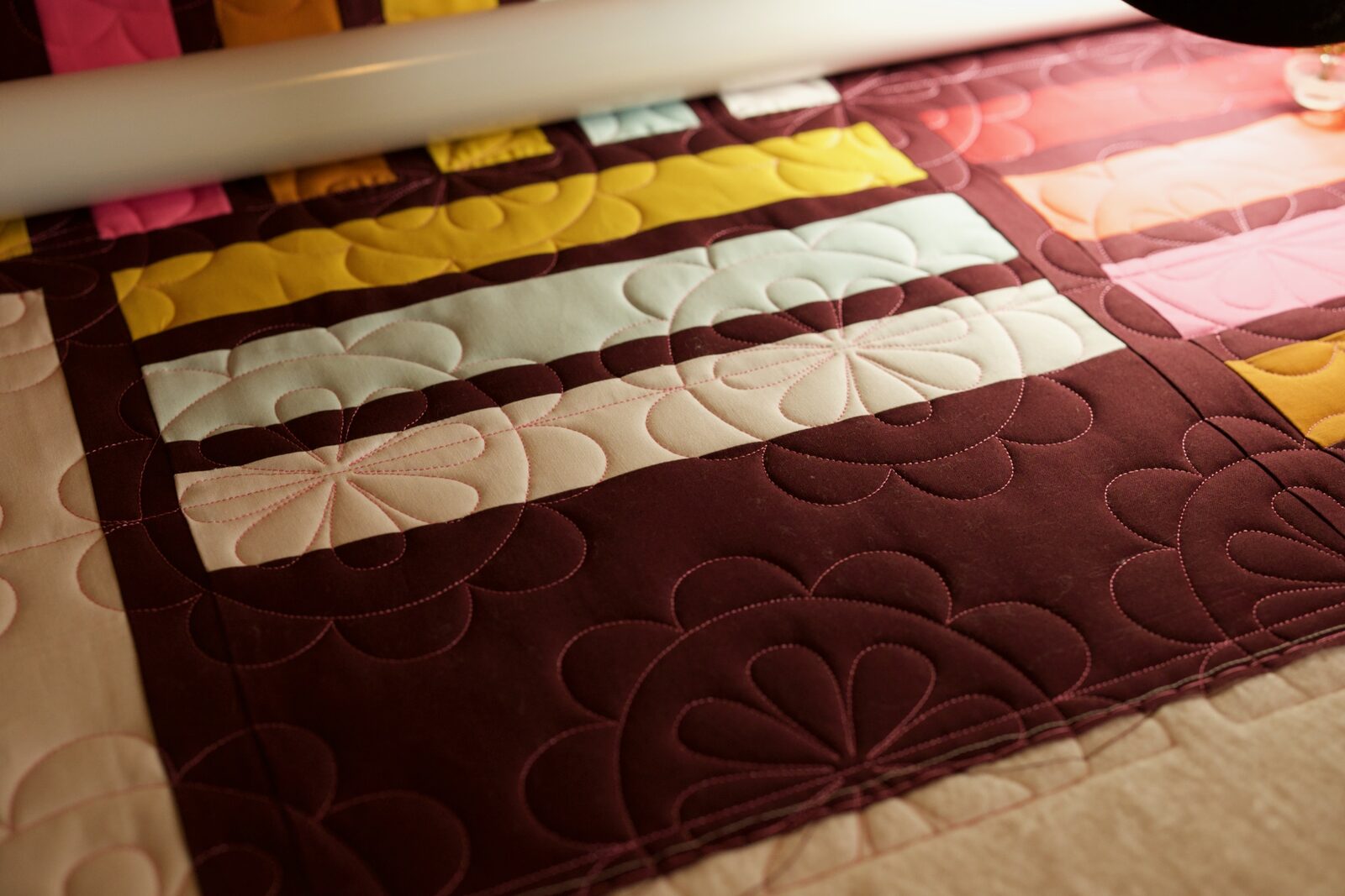 Petal quilting detail on burgundy and pastel fabric stripes