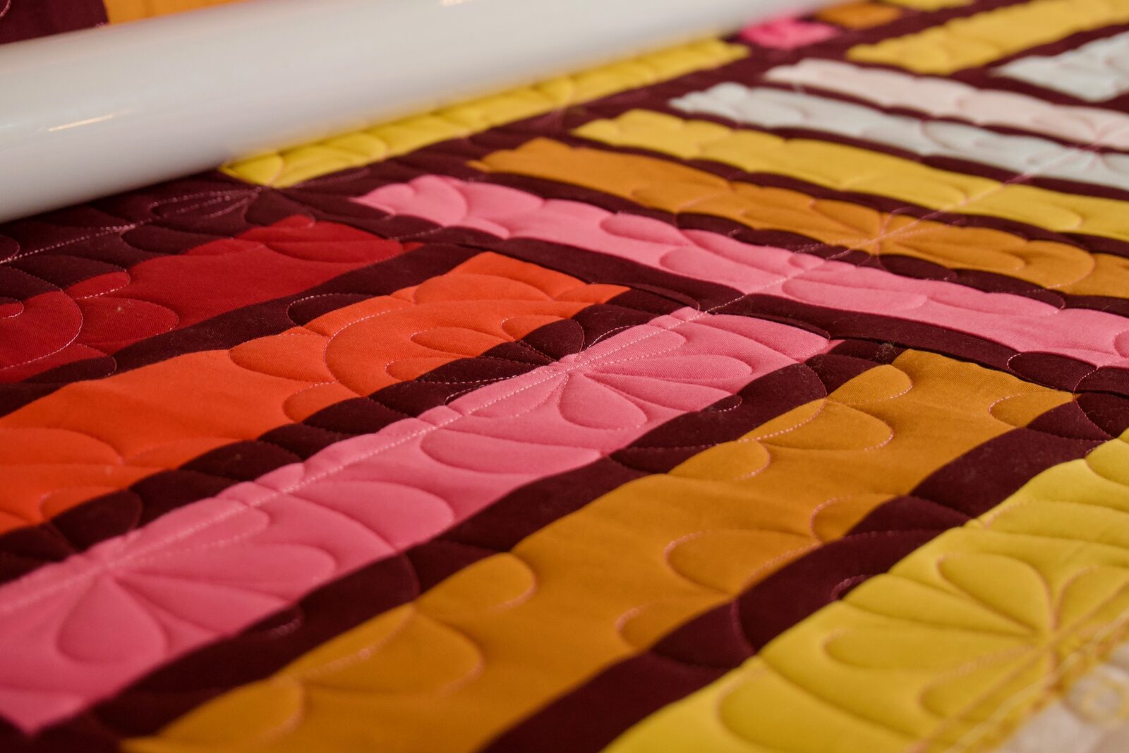 Petal quilting detail on red, orange, and pink fabric stripes
