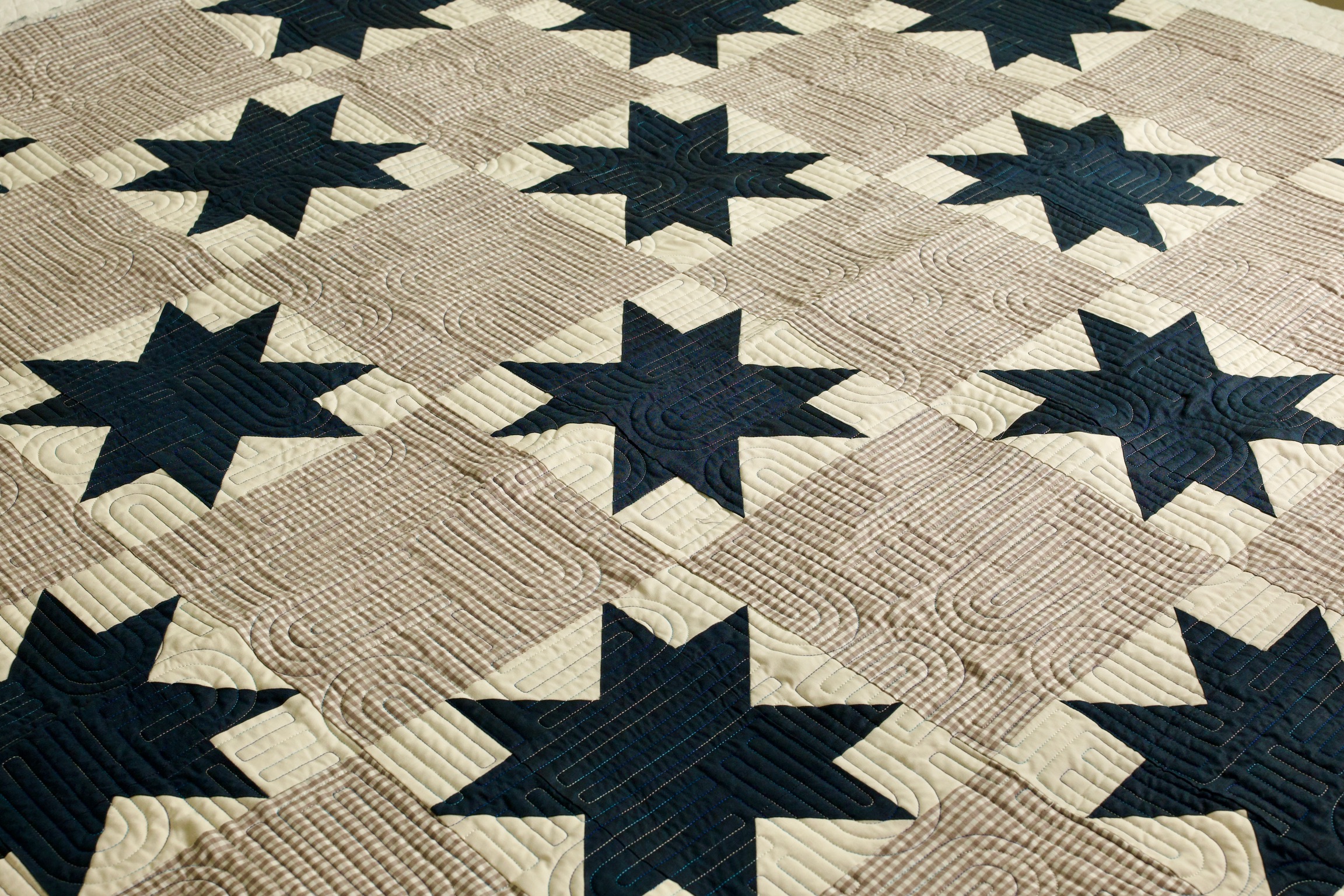 Rows of navy star blocks pieced with gingham squares on the design wall