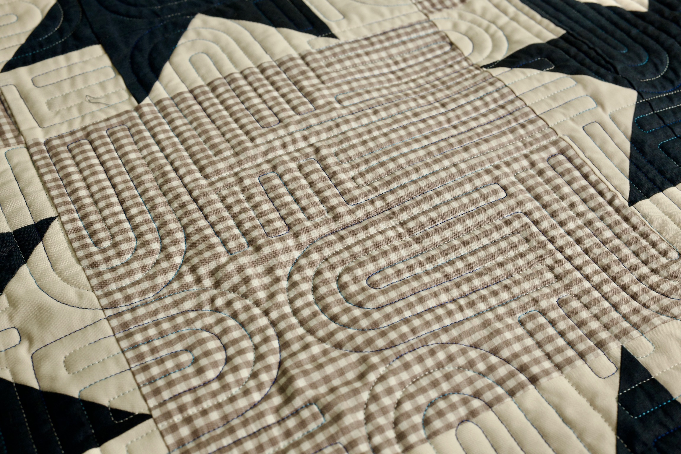 Diagonal detail of navy star blocks and gingham patchwork with allover quilting