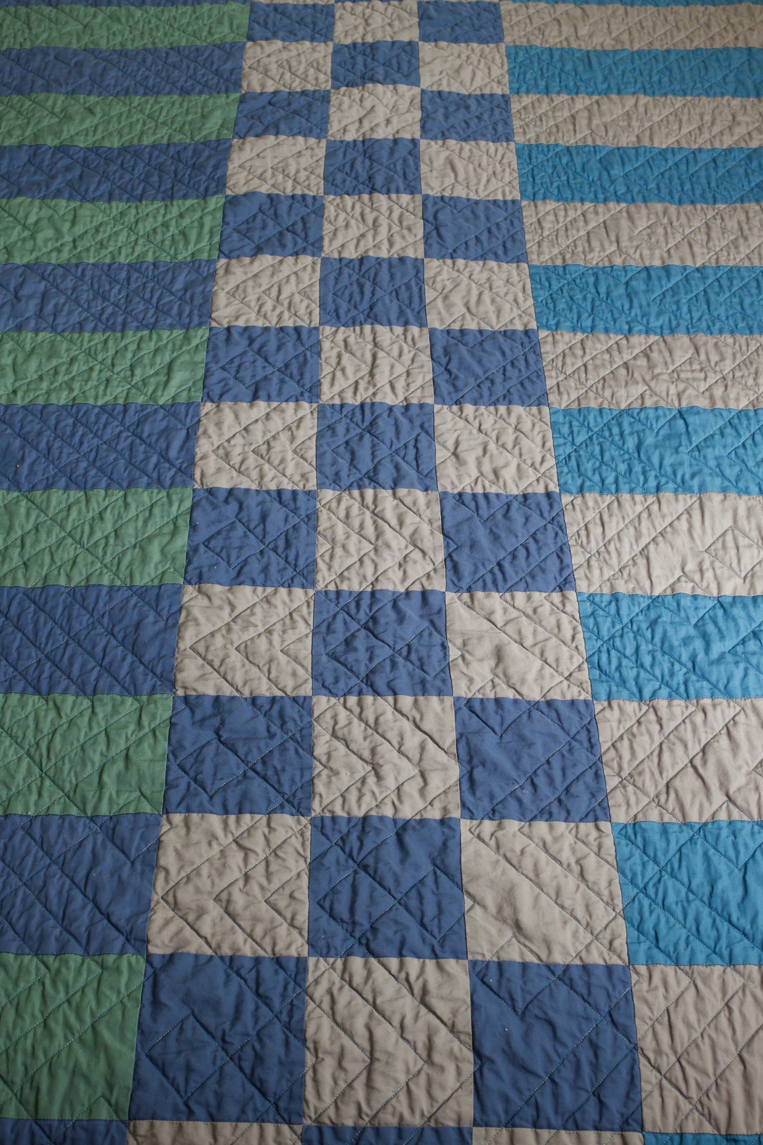 Blue, gray, and green rectangle patchwork with diagonal quilting stitches