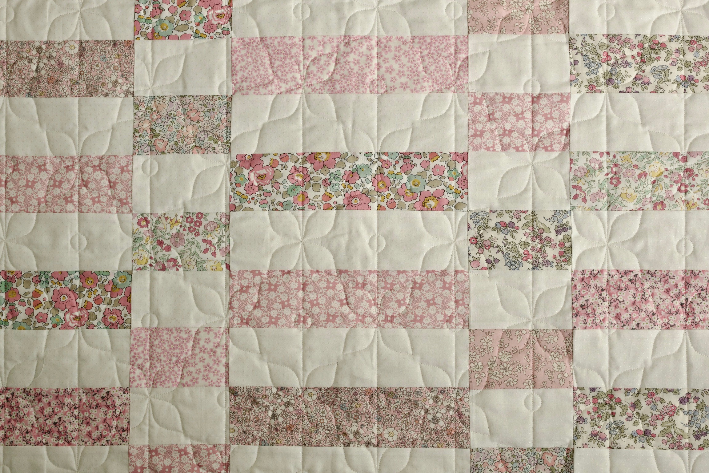Pink floral squares set on point with petal quilting between blocks