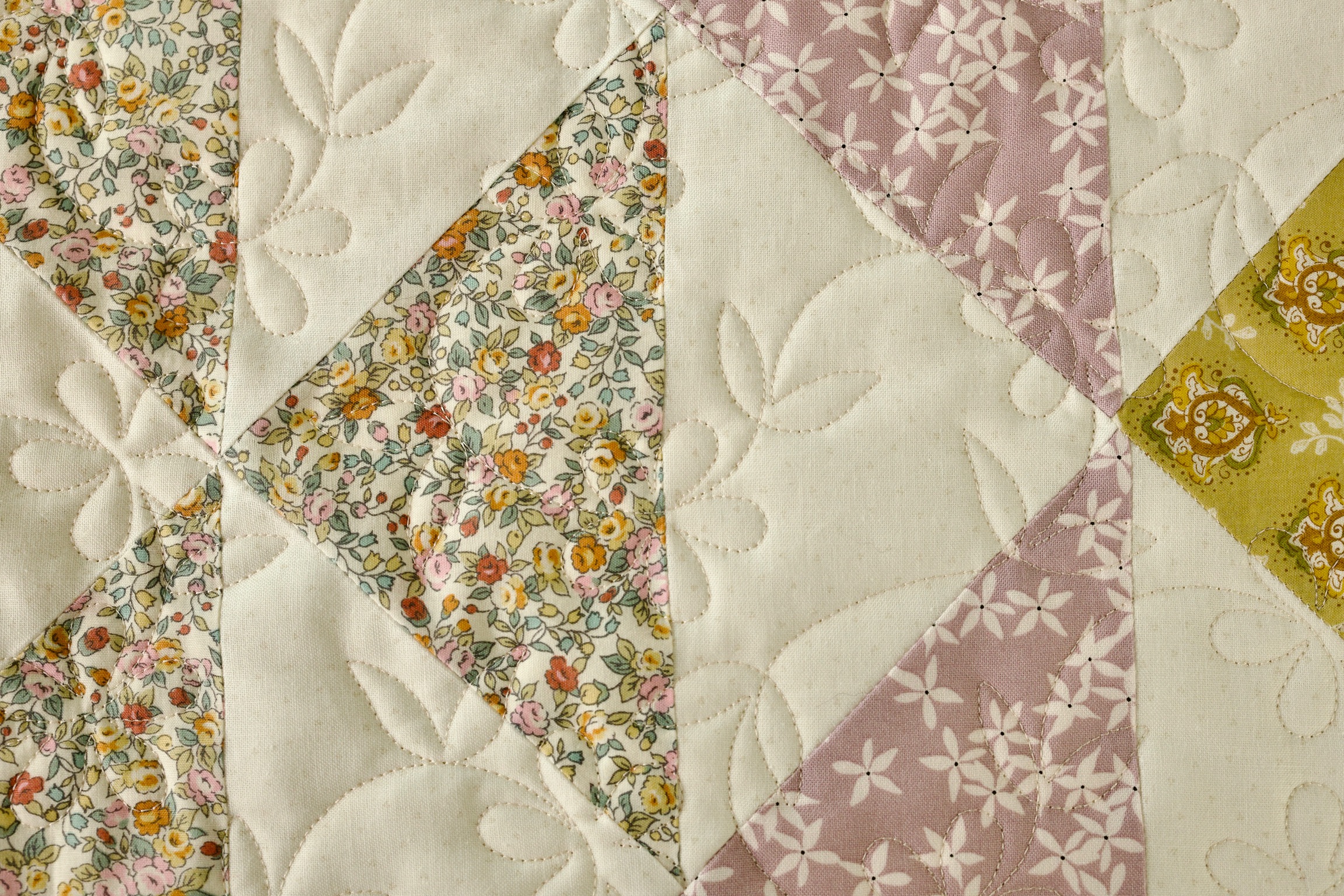 Close-up of floral triangle patchwork in dusty pink, olive, and cream