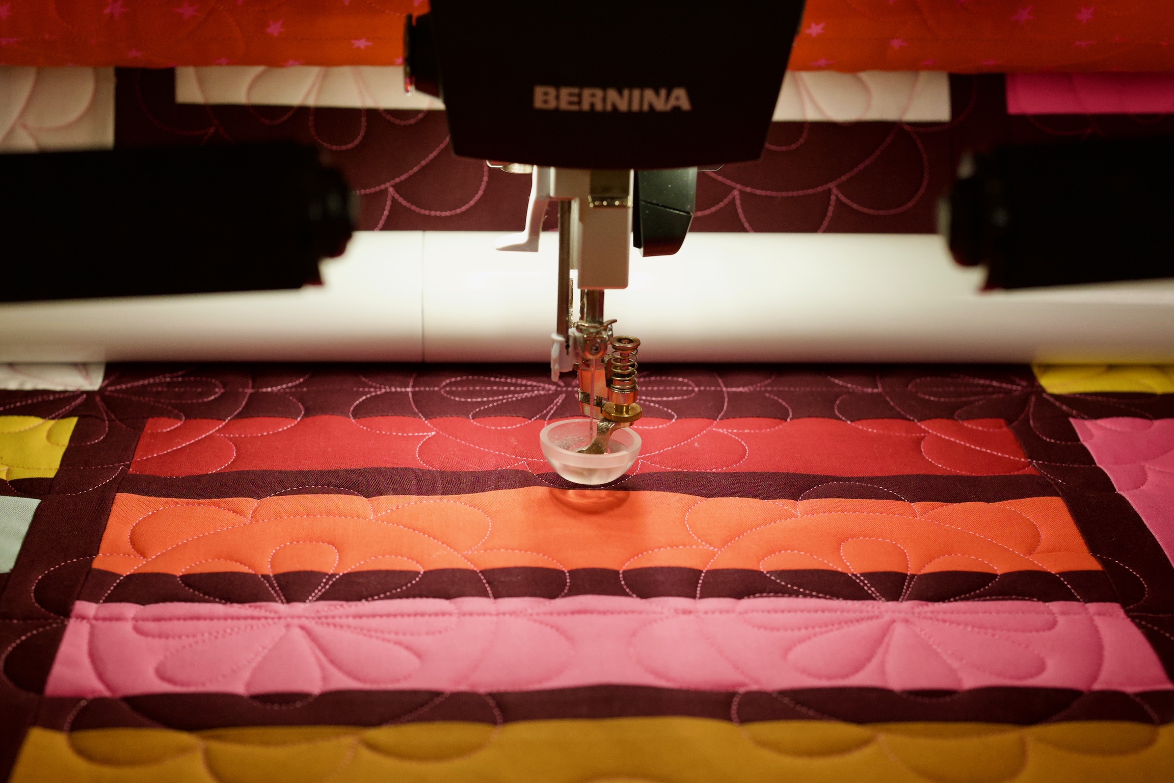 Bernina longarm machine stitching the striped quilt, side view