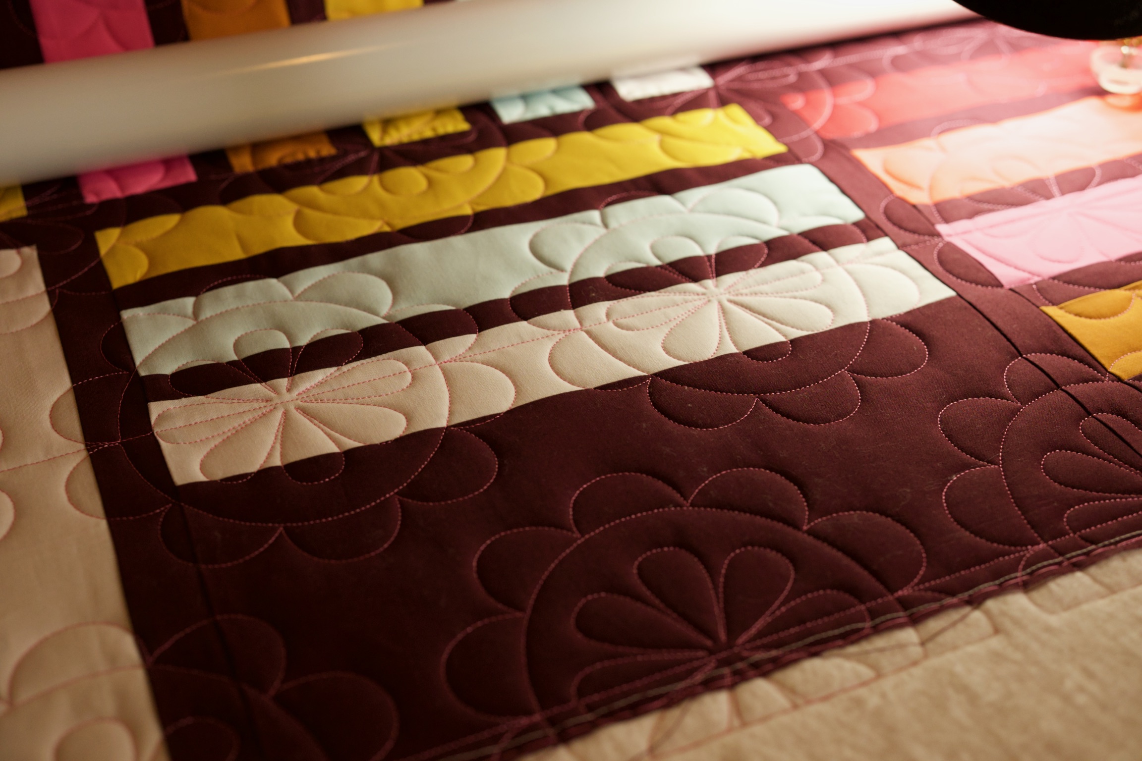 Petal quilting detail on burgundy and pastel fabric stripes