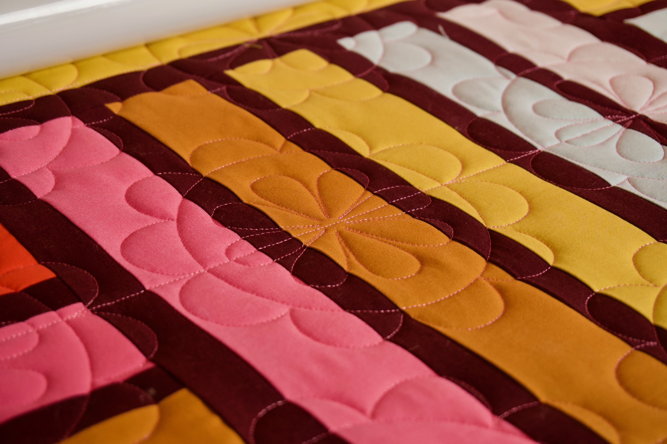 Petal quilting detail on pink, orange, and cream fabric stripes