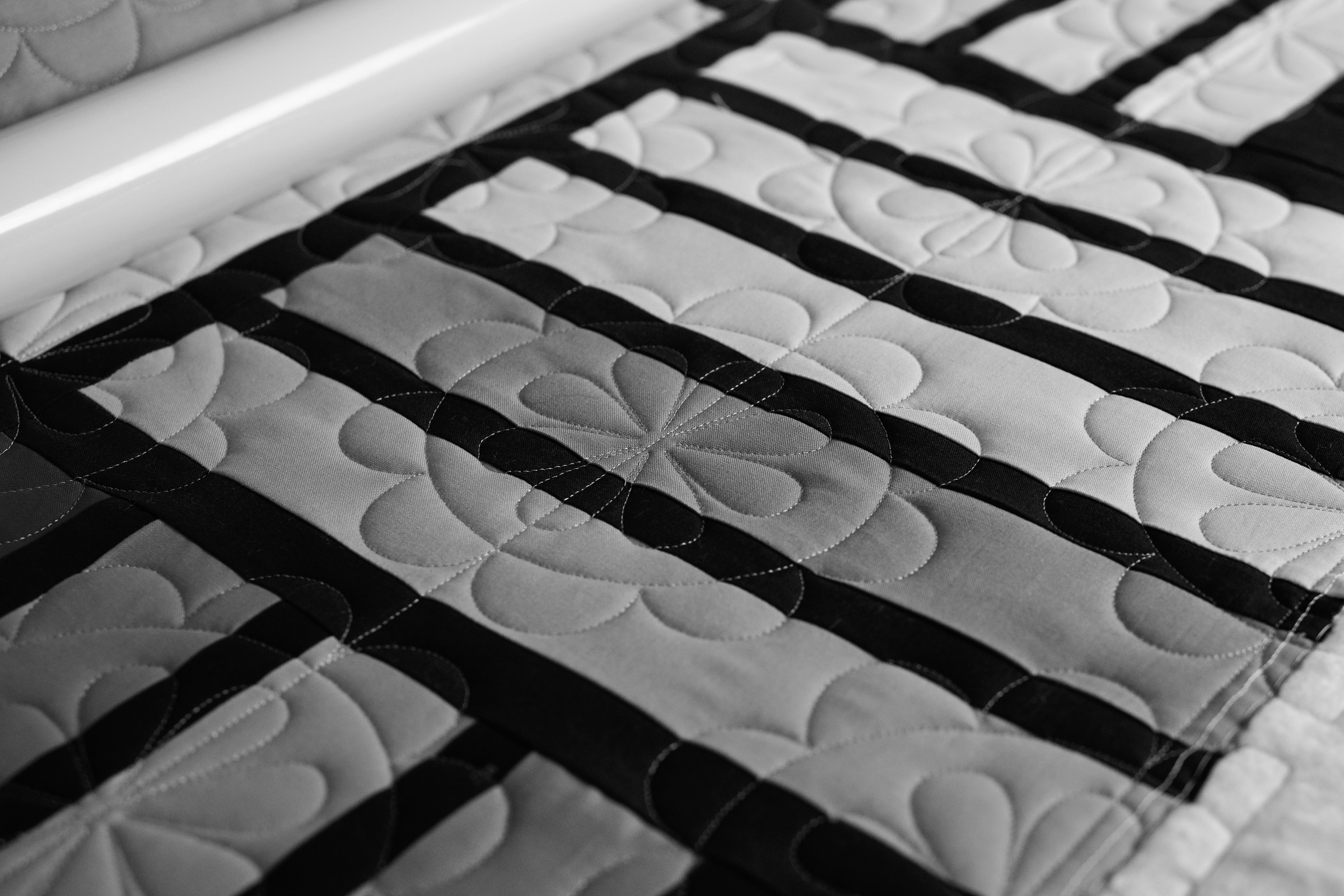 Black and white detail of the striped quilt's petal quilting pattern