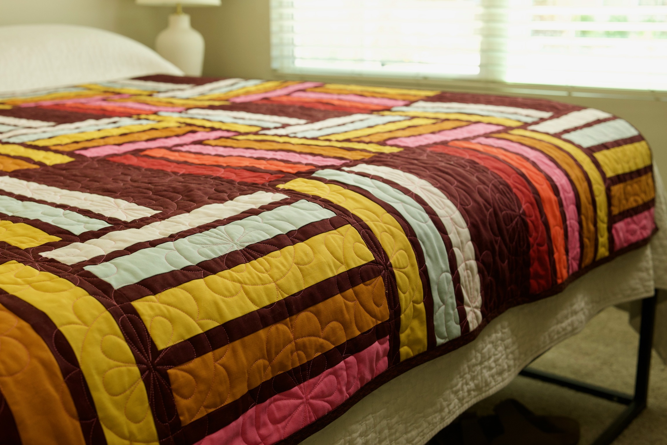 Finished striped and rectangle quilt draped over a bed