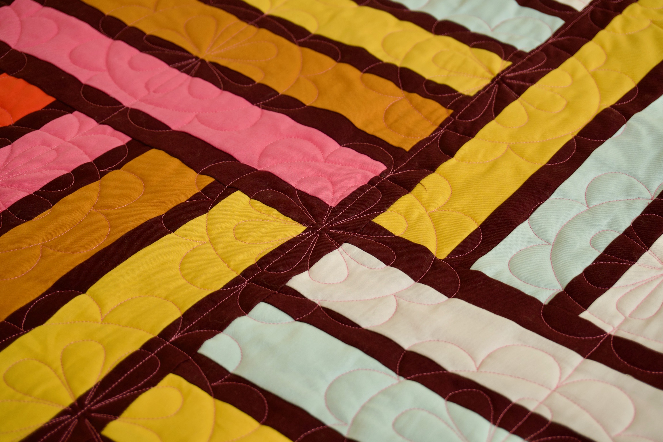 Diagonal detail of woven rectangle patchwork in mustard, coral, and mint